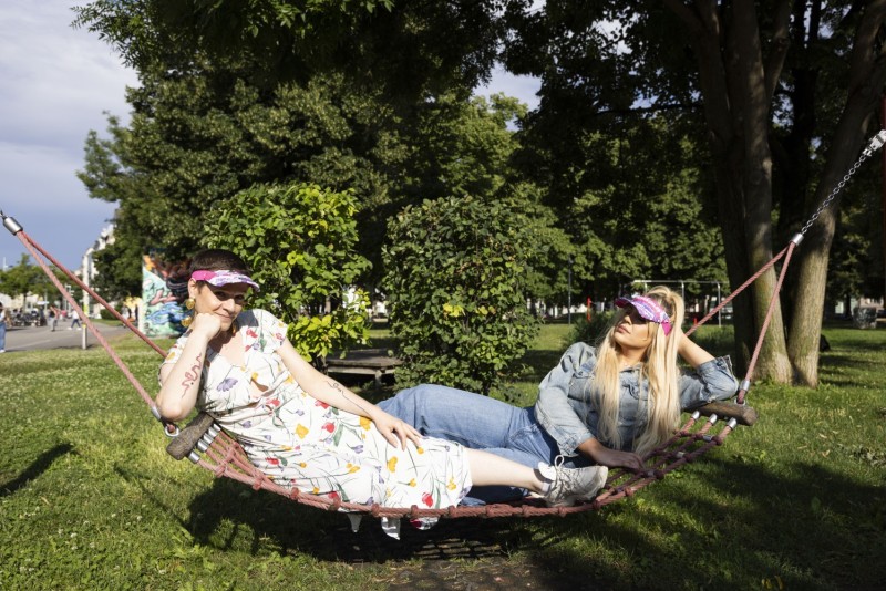 WIENWOCHE 2023: Queer Anger by Sigmund Hutter. Image showing the two models Jolanda Helena Resch and Stefanie Stankovic lying in a hammock and wearing the sun caps. © WIENWOCHE, Marisel Orellana Bongola